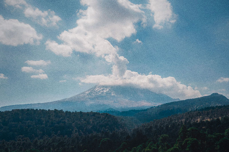 Volcán Popocatépetl con columna de humo sobre bosque de la Sierra Mixteca Alta en Puebla